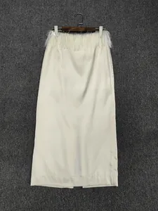 Detailed view of cream satin midi skirt featuring delicate feather trim and side slit