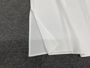 Detail view of the side slit and fine hem stitching on a white linen-blend sleeveless top