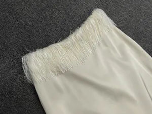 Detailed macro shot of premium ivory satin skirt hem featuring elegant long tassel fringe
