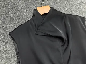 Detail of black satin sleeveless top featuring a sleek draped high-neck crossover design