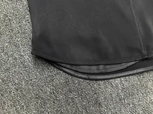 Detail shot of the curved hem and smooth stitching on this black satin sleeveless top