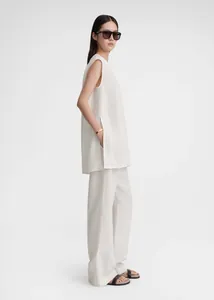 Detail of white sleeveless tunic featuring a high side slit and relaxed minimalist fit
