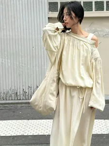 Detail of off-white off-shoulder dress featuring fine pleats and adjustable drawstring waist