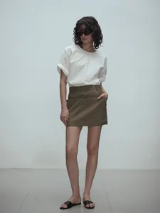 Detail of high-waist A-line skirt in olive green paired with white cotton short sleeve shirt