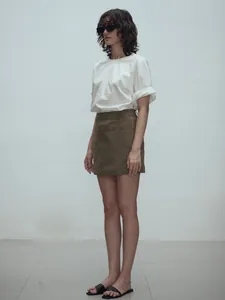 Detail of high-waist A-line mini skirt with structural layering in olive green