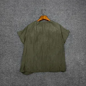 Detail of dark green pleated texture fabric on a minimalist short-sleeved round-neck top