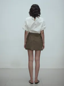 Back view of olive green high-waisted A-line mini skirt with large pockets and white top