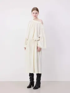Detail of off-white long sleeve dress featuring asymmetric off-shoulder neck and waist drawstring