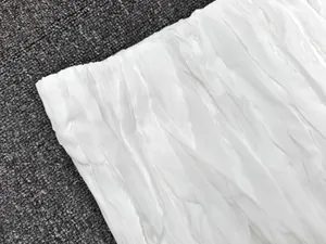 Close-up of white pleated fabric with fine vertical textures and soft silky luster