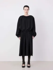 Detail of minimalist black long sleeve dress with drawstring waist and pleated neckline