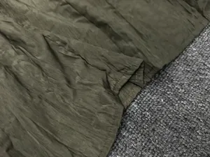 Detail of olive green crinkled fabric texture and neat double-stitched hem on the top