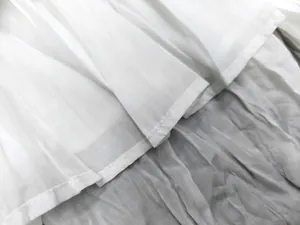 Macro detail of white pleated texture and precision stitching on short sleeve top