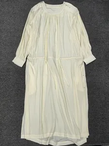 Detail of minimalist cream long-sleeve dress with round neck and drawstring waist