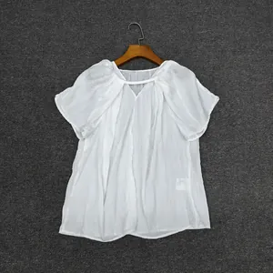 Detail of white pleated short-sleeve top with V-neckline and tie-front closure
