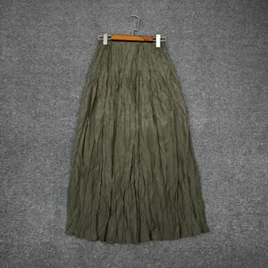 Detailed view of dark green pleated skirt with textured fabric hanging on a wooden hanger
