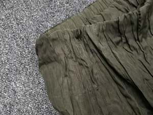 Macro detail of elastic waistband on dark olive green pleated fabric with texture