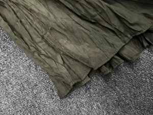 Macro shot of olive green pleated fabric texture with neat machine-stitched hem