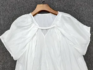 Detail of white short-sleeve top featuring unique pleated texture and V-neckline design