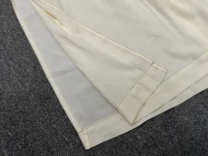 Detailed view of cream-colored dress hem featuring side slit and neat parallel stitching