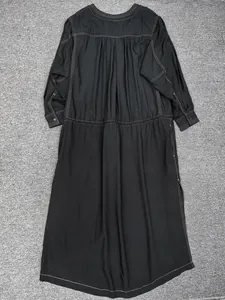 Detail of black long-sleeved dress featuring white contrast stitching and pleated waistline
