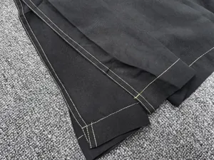 Detail of contrast white double stitching on black loose-fit long sleeve dress hem