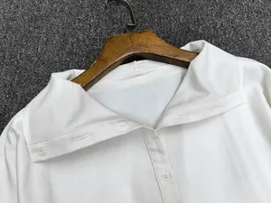 Close-up of a white cotton shirt collar and buttoned placket on a wooden hanger