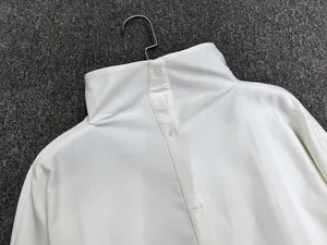 Detailed back view of white loose shirt showing row of buttons on the high collar