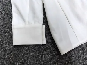 Close-up of white long-sleeve shirt cuff with neat stitching and fine twill fabric texture