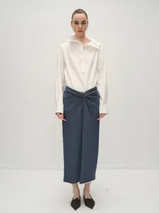 Detail of white cotton stand-collar shirt and navy wrap skirt with knotted waist detail