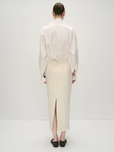Back view of a white long sleeve shirt with box pleats and a cream slit midi skirt