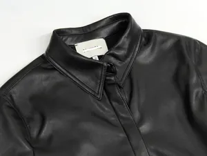 Detailaufnahme eines schwarzen Lederkleides mit klassischem Kragen und weißem S-Label