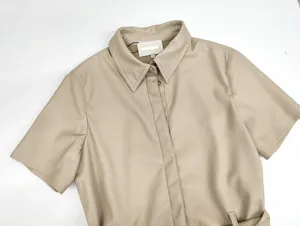 Detail eines beigen Leder-Kurzarmhemdes mit klassischem Kragen und internem Größenetikett