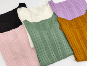 Flat lay of ribbed crewneck knit tops in six different colors on white background