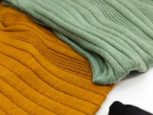 Close-up of ribbed knit texture on slim fit tops in sage green and mustard yellow