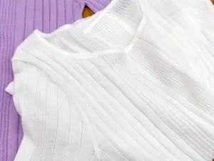 Close-up of ribbed knit fabric texture on white and lavender crewneck sweaters