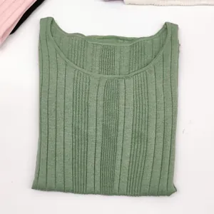 Detailed macro view of light green ribbed knit texture and soft round neckline
