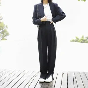 Close-up of high-waisted wide-leg trousers in black with a draped minimalist silhouette