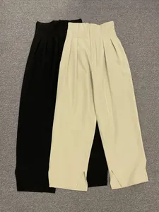 Detail view of high waist wide leg trousers with pleated waist and side slit at hem
