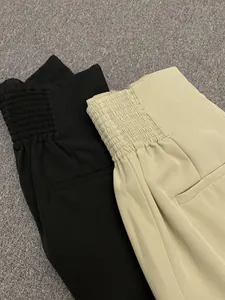 Detail of high waist trousers showing elastic waistband and decorative back pockets