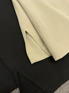 Detailed close-up of side slits on drape wide-leg trousers in beige and black colors