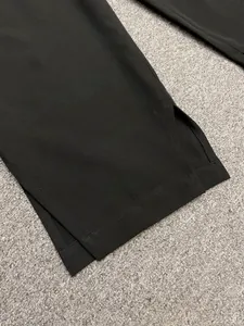 Detailed macro view of side slit hem on black high-waisted wide-leg drape trousers