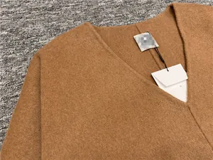 Macro view of camel V-neck wool top showing high-quality fabric texture and tag detail