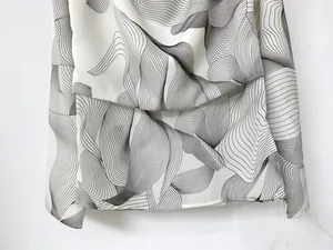 Close-up of lightweight chiffon fabric with abstract black wave print and soft drape