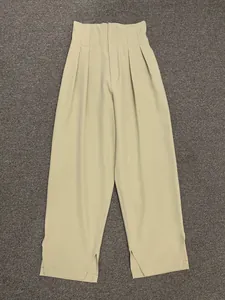 Detail view of khaki high waist trousers with elegant front pleats and side slit hems