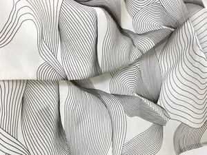 Detailed macro shot of white fabric featuring abstract black wave patterns and silk texture