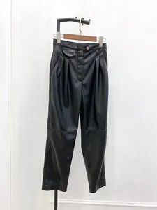 Detailed macro view of the high-waisted pleated leather trousers with a decorative button