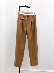 Close-up of brown faux leather high-waist pants with pleated details and button closure