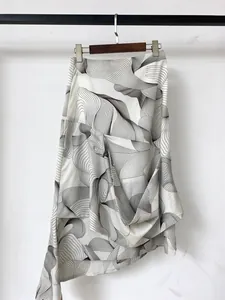 Detail of white asymmetric skirt featuring black abstract wave print and layered ruffles