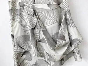 Detail shot of smooth satin fabric featuring elegant black abstract wavy print patterns