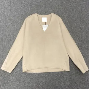 Detail view of the deep V-neckline and premium wool texture of the beige oversized top